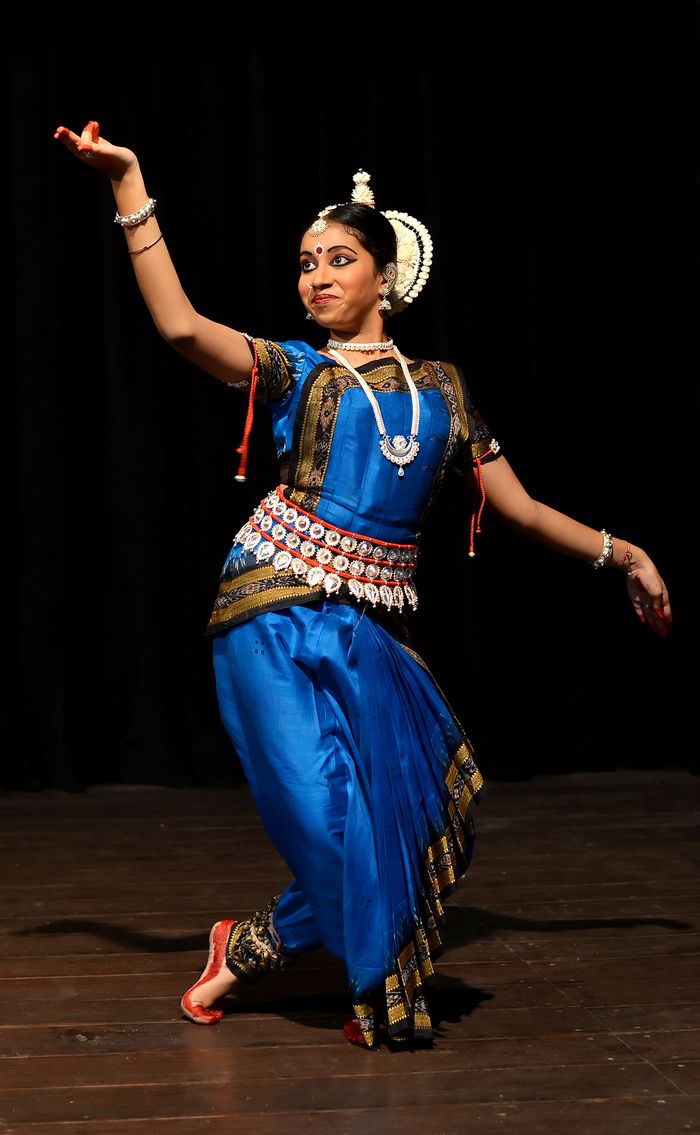 Odissi dancer on stage in a blue costume